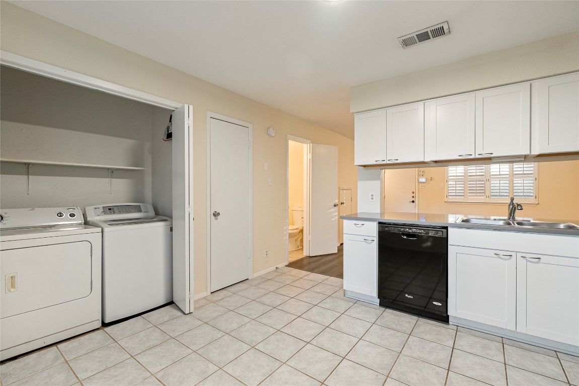 1408 Waterloo Trail, Unit A Austin, TX 78704 - Photo 6 of 13 Kitchen with white cabinets, black dishwasher, washing machine and clothes dryer, and light tile patterned floors