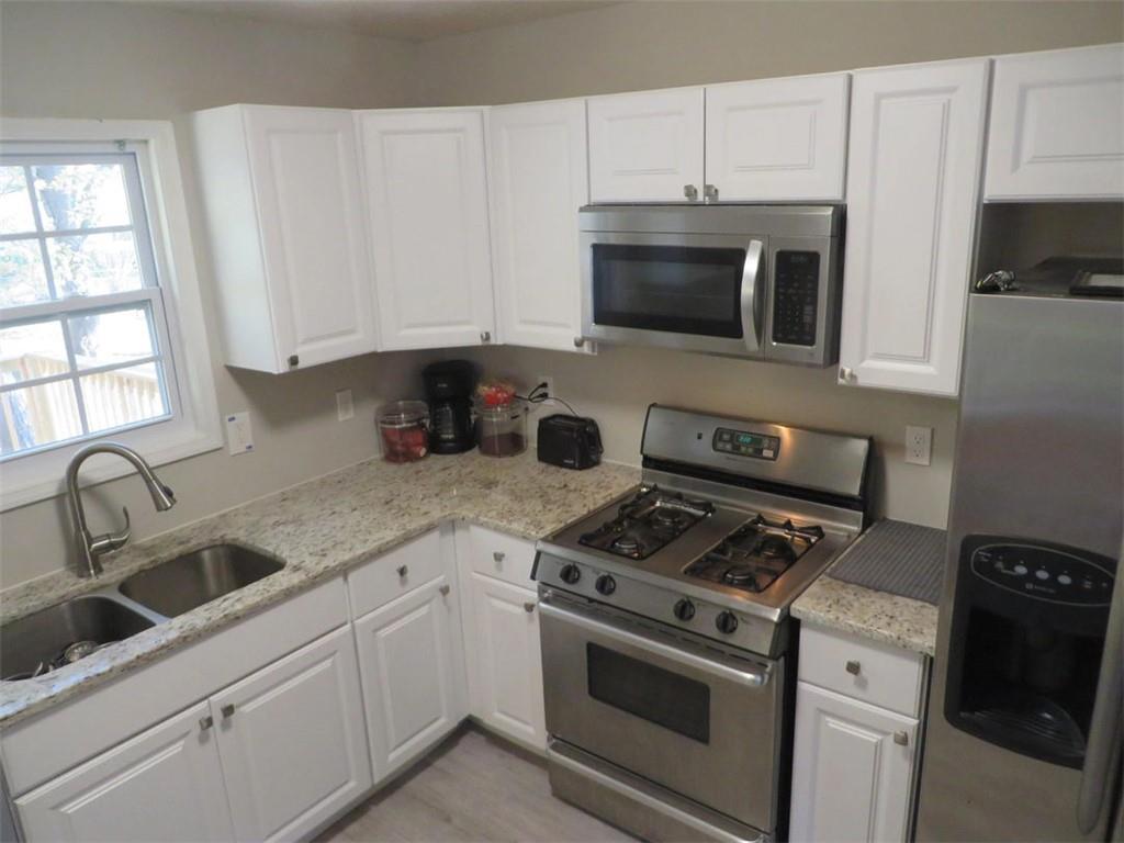 3000 Creel Road Atlanta, GA 30349 - Photo 4 of 52 a kitchen with granite countertop white cabinets and black appliances