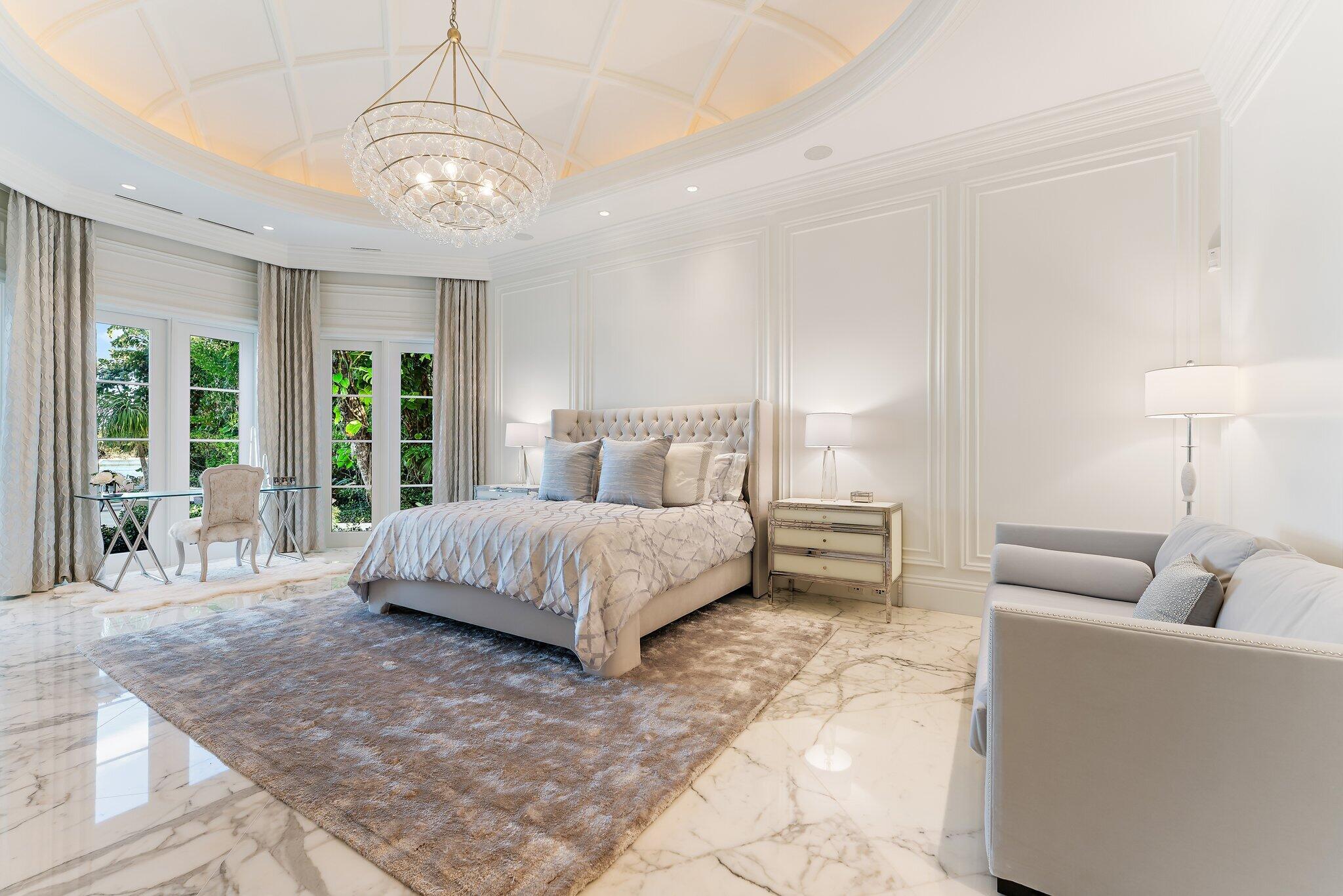 372 Regatta Drive Jupiter, FL 33477 - Photo 23 of 75 a spacious bedroom with a bed a chandelier and large window