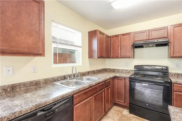 a view of an empty room with kitchen and a window