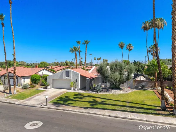 a front view of a house with a yard and palm trees