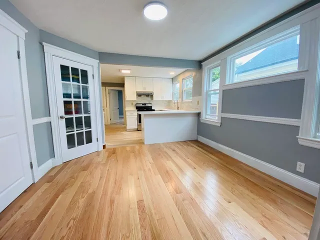 a view of a living room with kitchen island wooden floor and window
