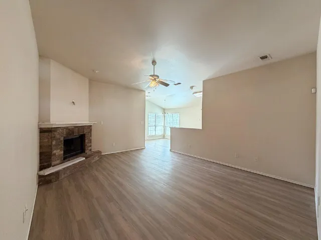 a view of an empty room with wooden floor fireplace and a window