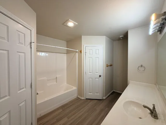 a bathroom with a tub shower and sink