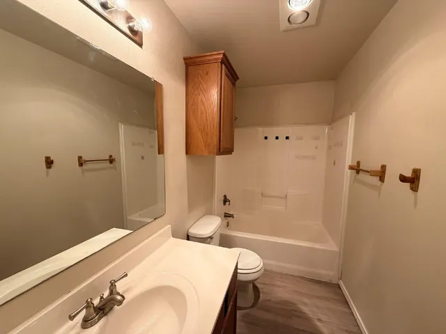 a bathroom with a granite countertop sink a toilet and shower