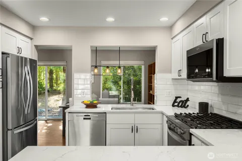 a kitchen with a sink a counter top space stainless steel appliances a window and cabinets