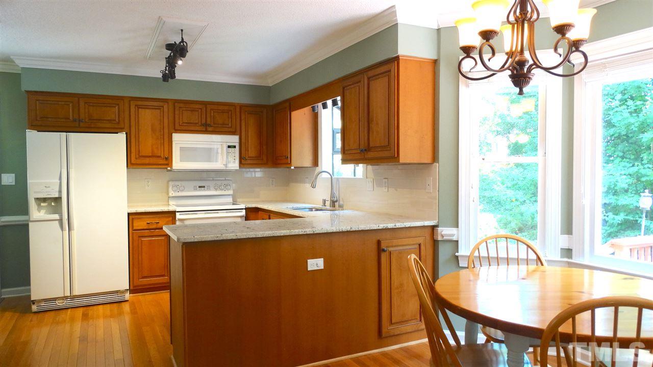 6812 Chasewick Circle Raleigh, NC 27615 - Photo 12 of 30 a kitchen with stainless steel appliances granite countertop a stove a refrigerator a sink dishwasher with a dining table and chair with wooden floor