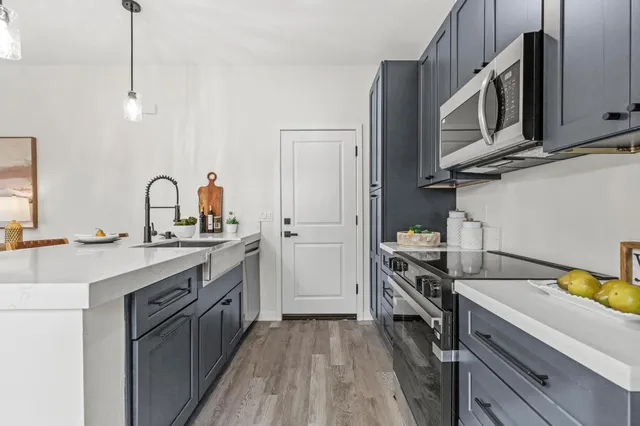 a kitchen with a table a stove and a clock on the wall