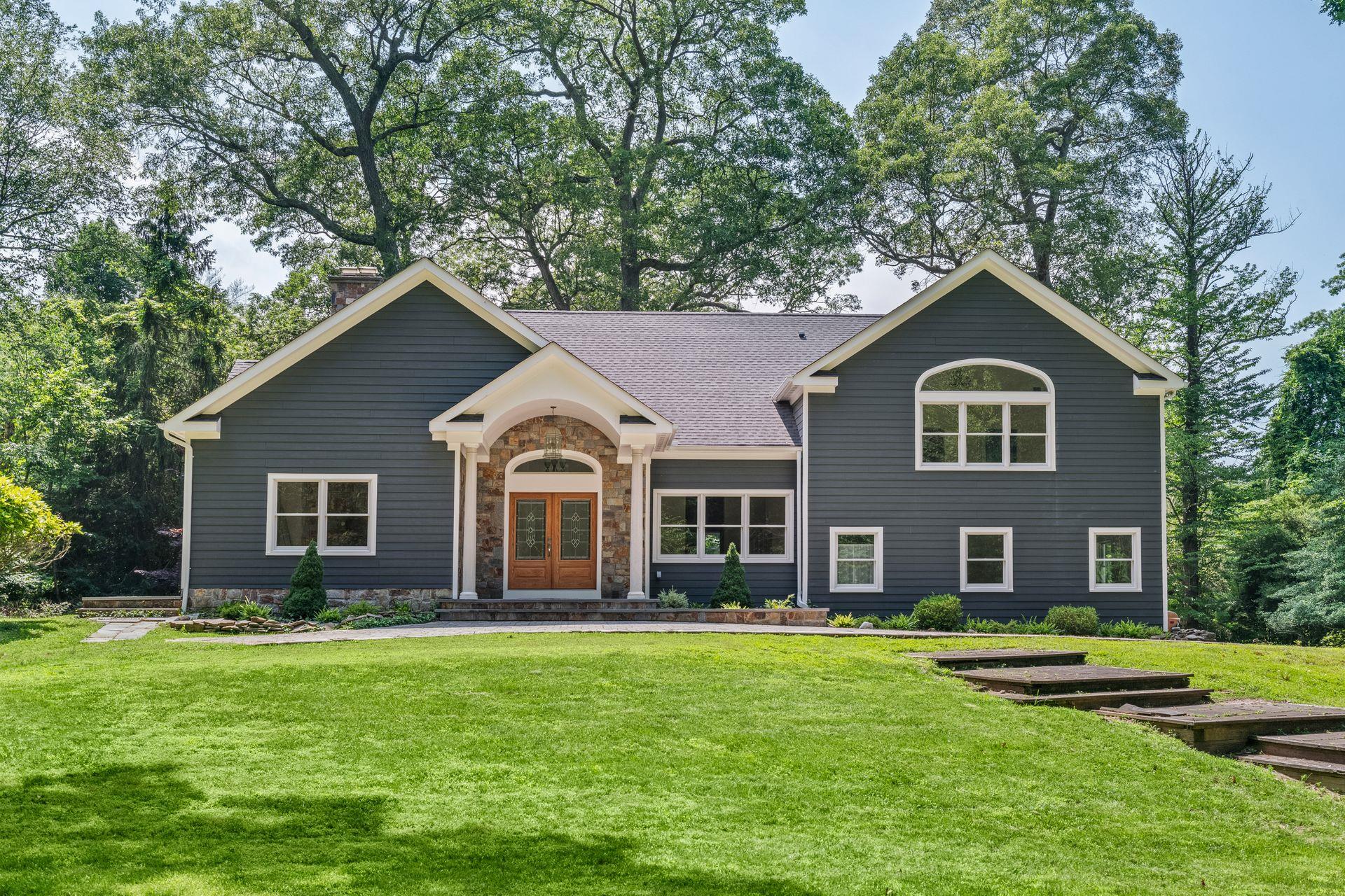 View of front of home with french doors, a chimney, a front yard, roof with shingles, and stone siding