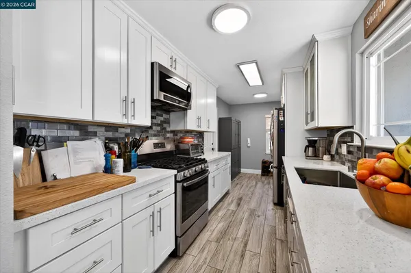 a kitchen with granite countertop a sink a counter top space stainless steel appliances and cabinets