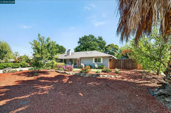 a backyard of a house with table and chairs under an umbrella