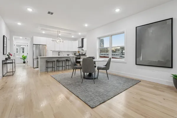 a dining room with furniture a rug a potted plant and a painting