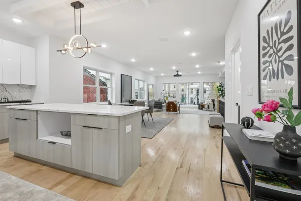 a very nice looking kitchen with granite countertop a stove top oven a sink a dining table and chairs with wooden floor