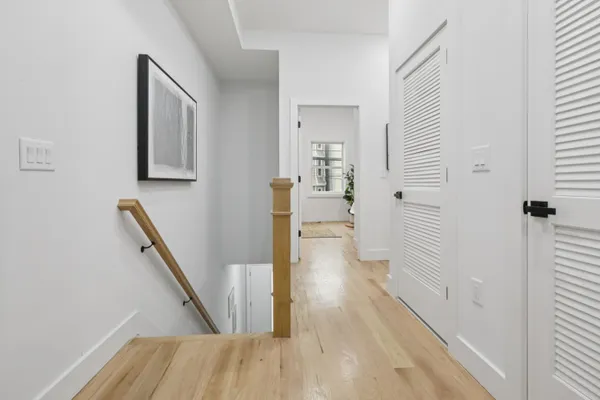 a view of a hallway with wooden floor and staircase