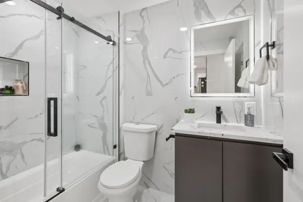 a bathroom with a granite countertop sink toilet a mirror and shower