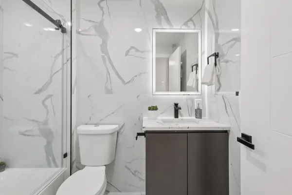 a bathroom with a granite countertop toilet sink and mirror