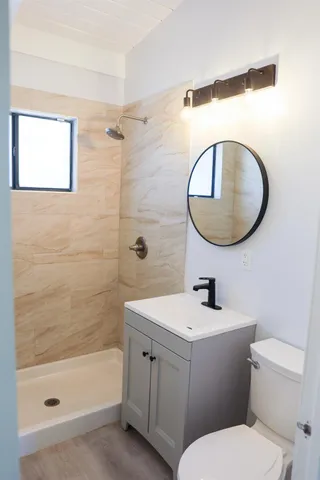 a bathroom with a toilet sink vanity tub and mirror