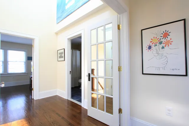 an entryway with wooden floor and a painting on the wall