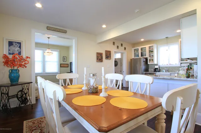 a dining room with stainless steel appliances kitchen island granite countertop a dining table chairs and a refrigerator