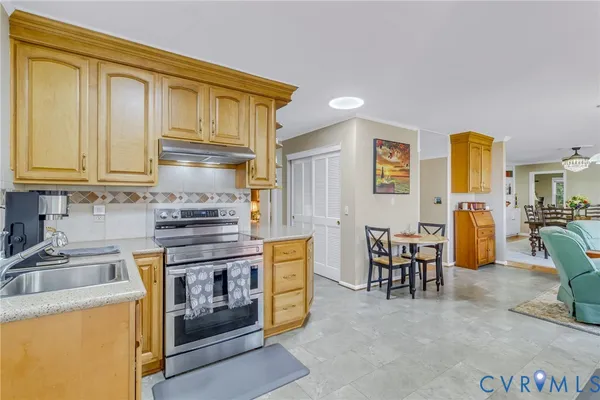 a kitchen with stainless steel appliances granite countertop a stove top oven a sink a dining table and chairs with wooden floor