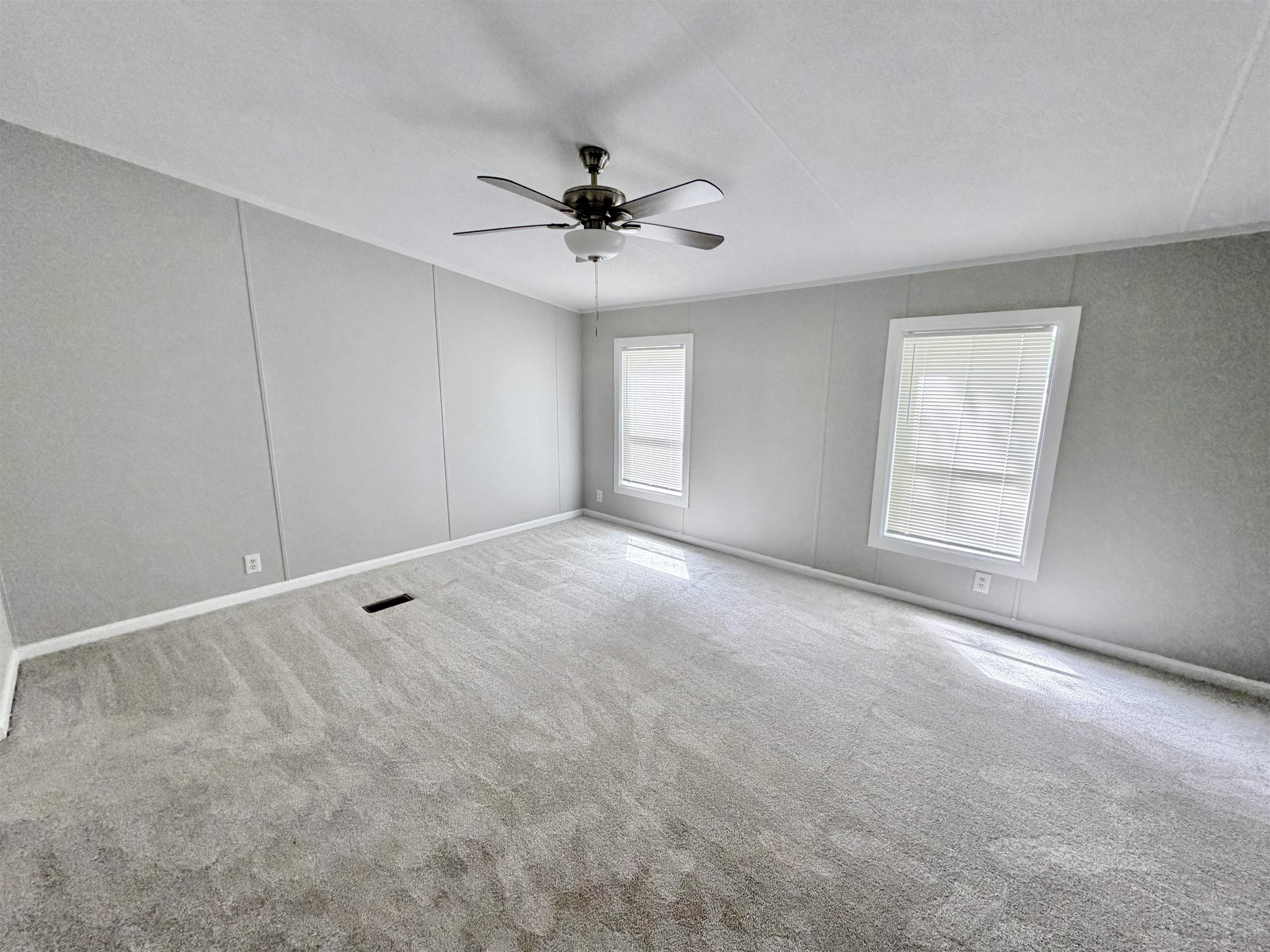 1655 Fayne Road Brighton, TN 38011 - Photo 11 of 28 Spacious room featuring light gray walls, two windows with white blinds, a ceiling fan with light fixture, and plush gray carpeting