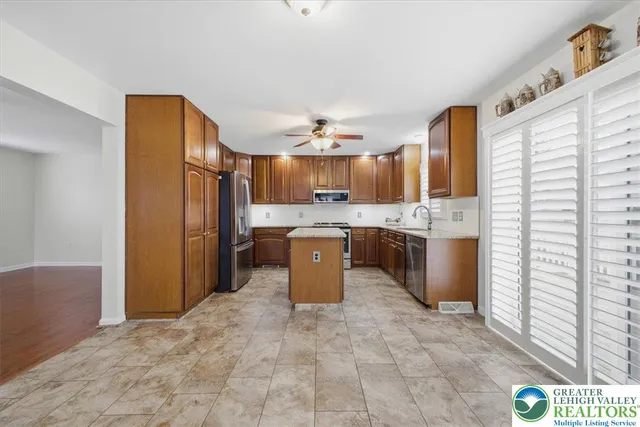 a kitchen with stainless steel appliances granite countertop a refrigerator a stove and a sink with cabinets