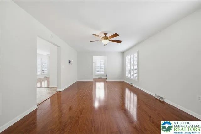 a view of an empty room with a window and wooden floor
