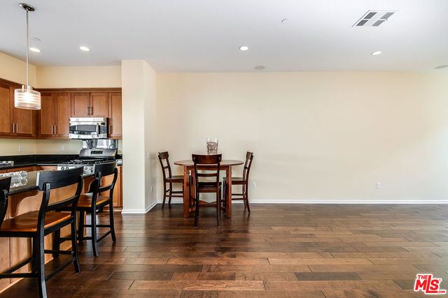 a kitchen with stainless steel appliances a dining table chairs and stove top oven with wooden floor