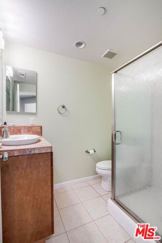 a bathroom with a granite countertop sink a toilet and a shower