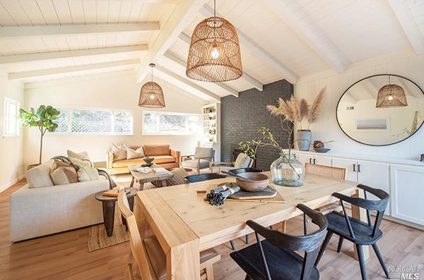 a living room with couches a fireplace and a dining table with wooden floor