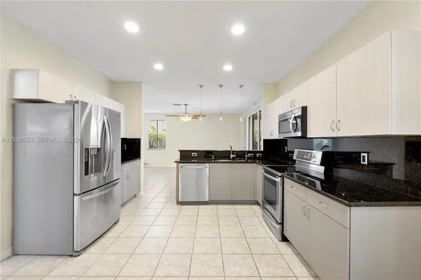 a kitchen with a refrigerator a sink a stove top oven and cabinets