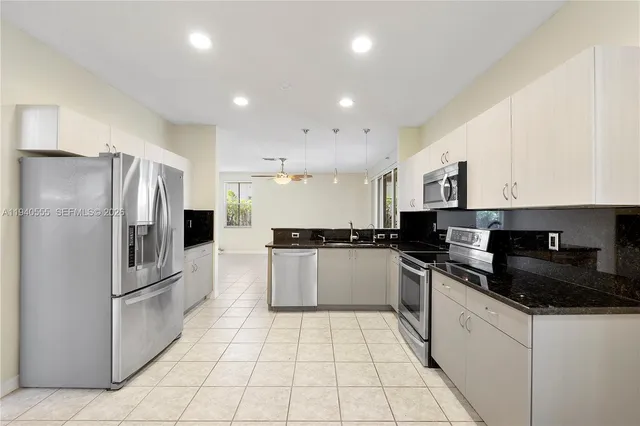 a kitchen with a refrigerator a sink a stove top oven and cabinets