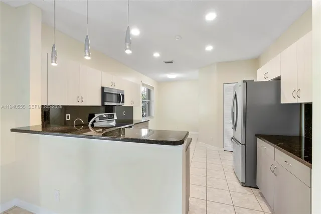 a modern kitchen with stainless steel appliances granite countertop a sink and a refrigerator