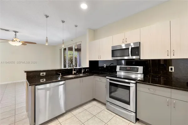 a kitchen with stainless steel appliances granite countertop a sink a stove a microwave and cabinets