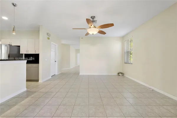 a view of an empty room and kitchen with a ceiling fan