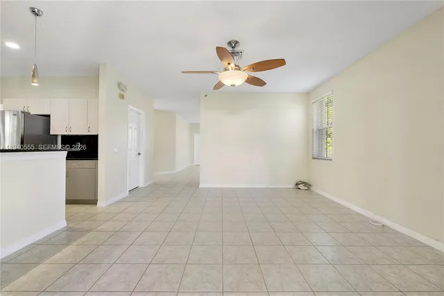 a view of an empty room and kitchen with a ceiling fan