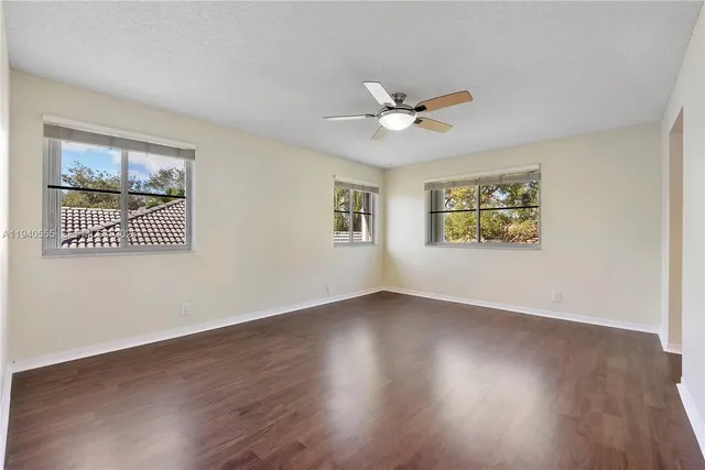 a view of an empty room with a window and wooden floor