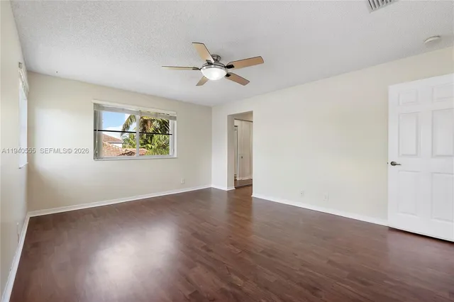 an empty room with wooden floor ceiling fan and windows