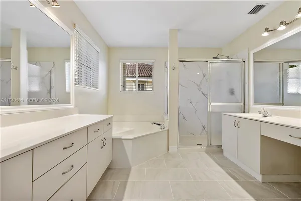 a spacious bathroom with a double vanity sink a mirror a bathtub and shower