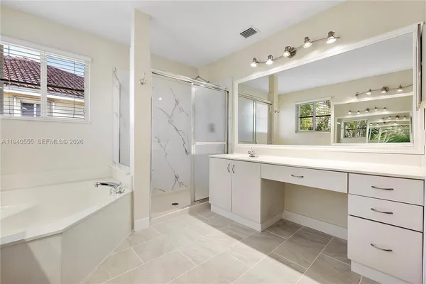 a bathroom with a tub sink shower and mirror