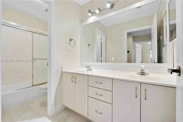 a bathroom with a double vanity sink mirror and next to a window