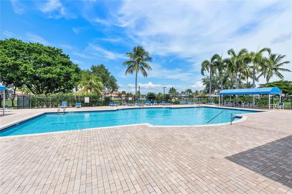 a view of swimming pool with a yard and palm trees