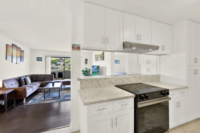 a kitchen with granite countertop a stove and white cabinets