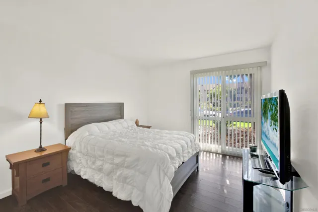a bedroom with a bed and a flat tv screen on dresser