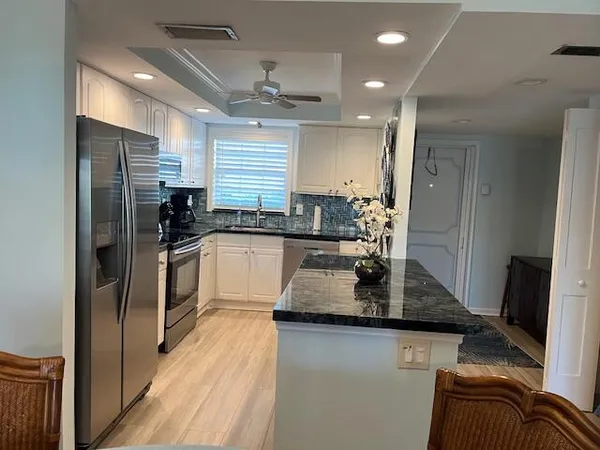 a kitchen with granite countertop a refrigerator a sink a stove a microwave a counter top space and cabinets