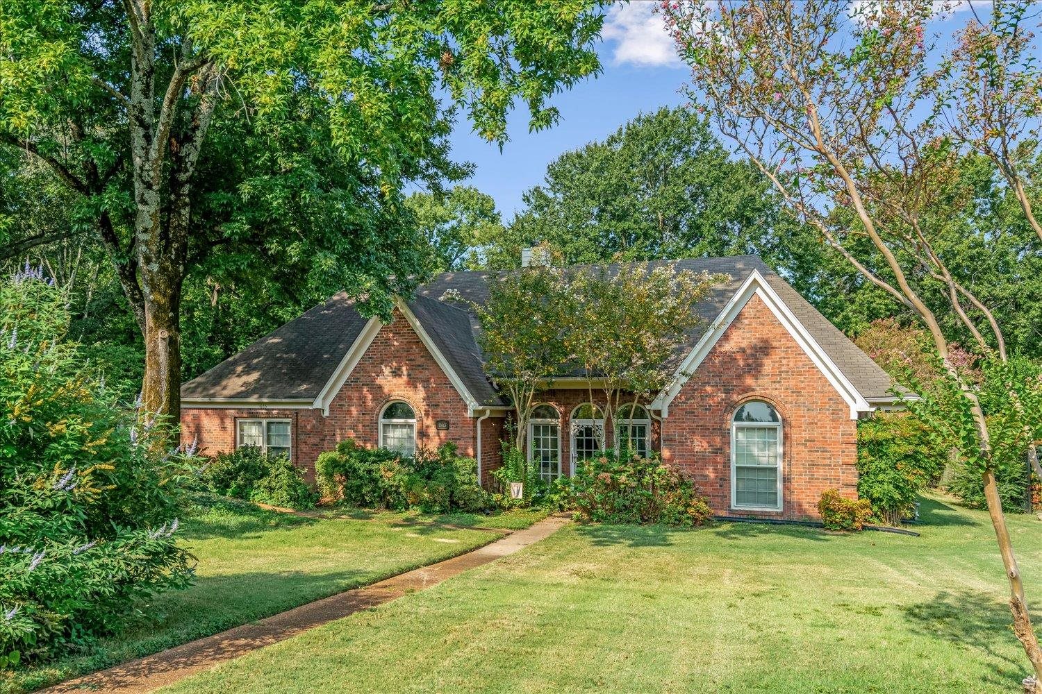 a front view of a house with a yard and trees