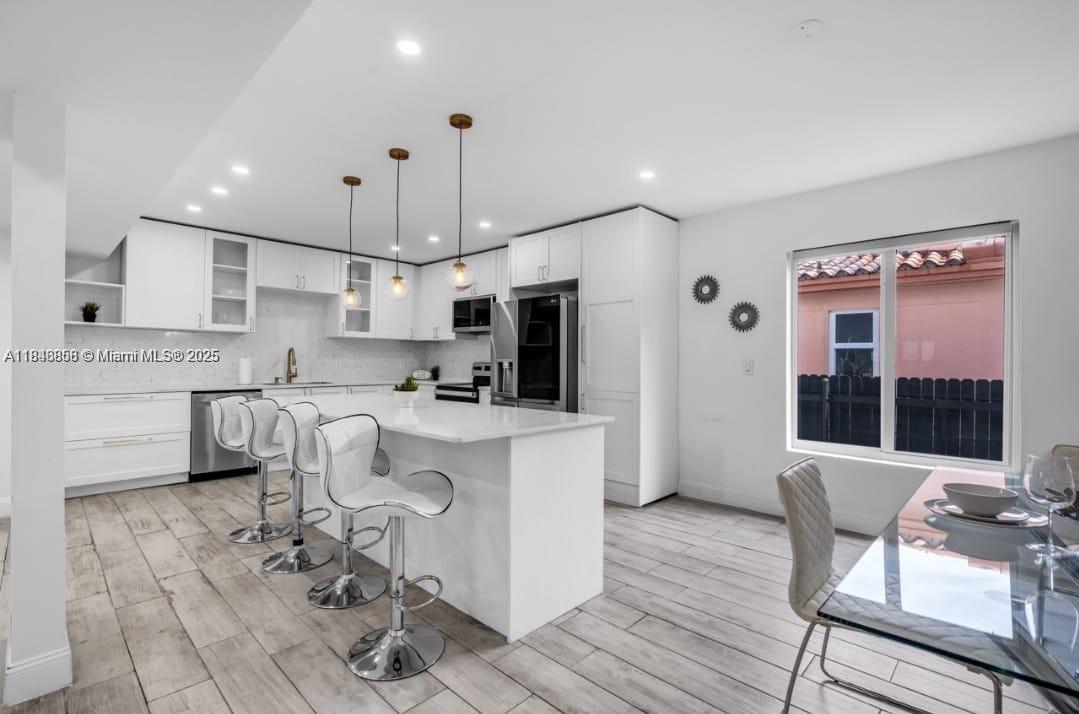 a kitchen with kitchen island stainless steel appliances a stove a sink a oven a dining table and chairs