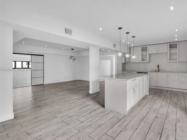 a large white kitchen with a refrigerator a sink dishwasher and a stove with wooden floor