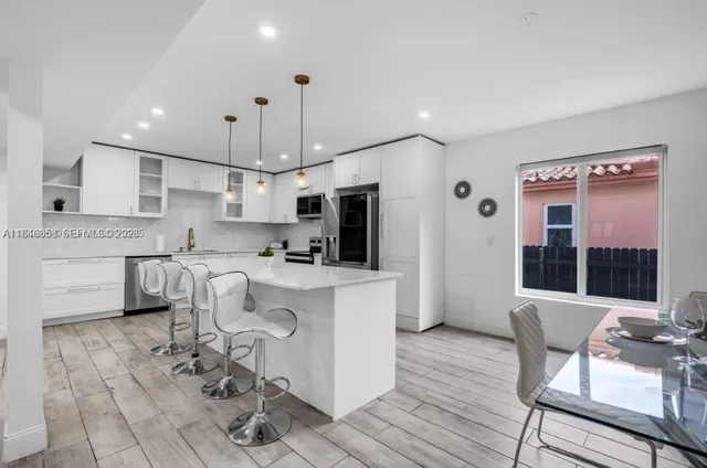 a kitchen with kitchen island stainless steel appliances a stove a sink a microwave a refrigerator and chairs