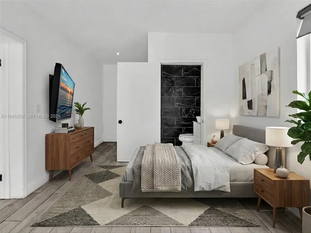 a bedroom with a bed a couch and a flat screen tv